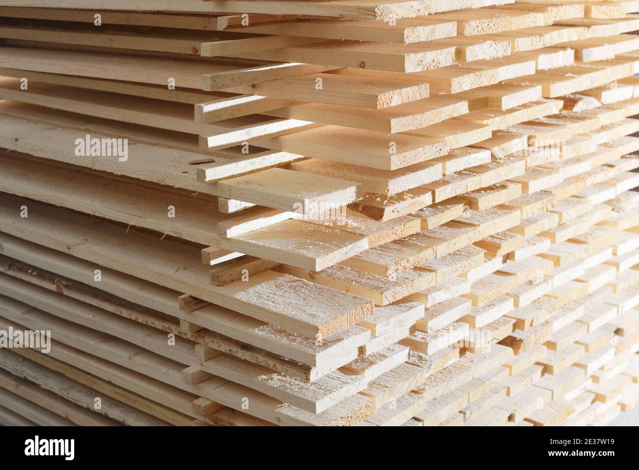 Wooden boards are stacked in a sawmill or carpentry shop. Drying and marketing of wood. Stock Photo