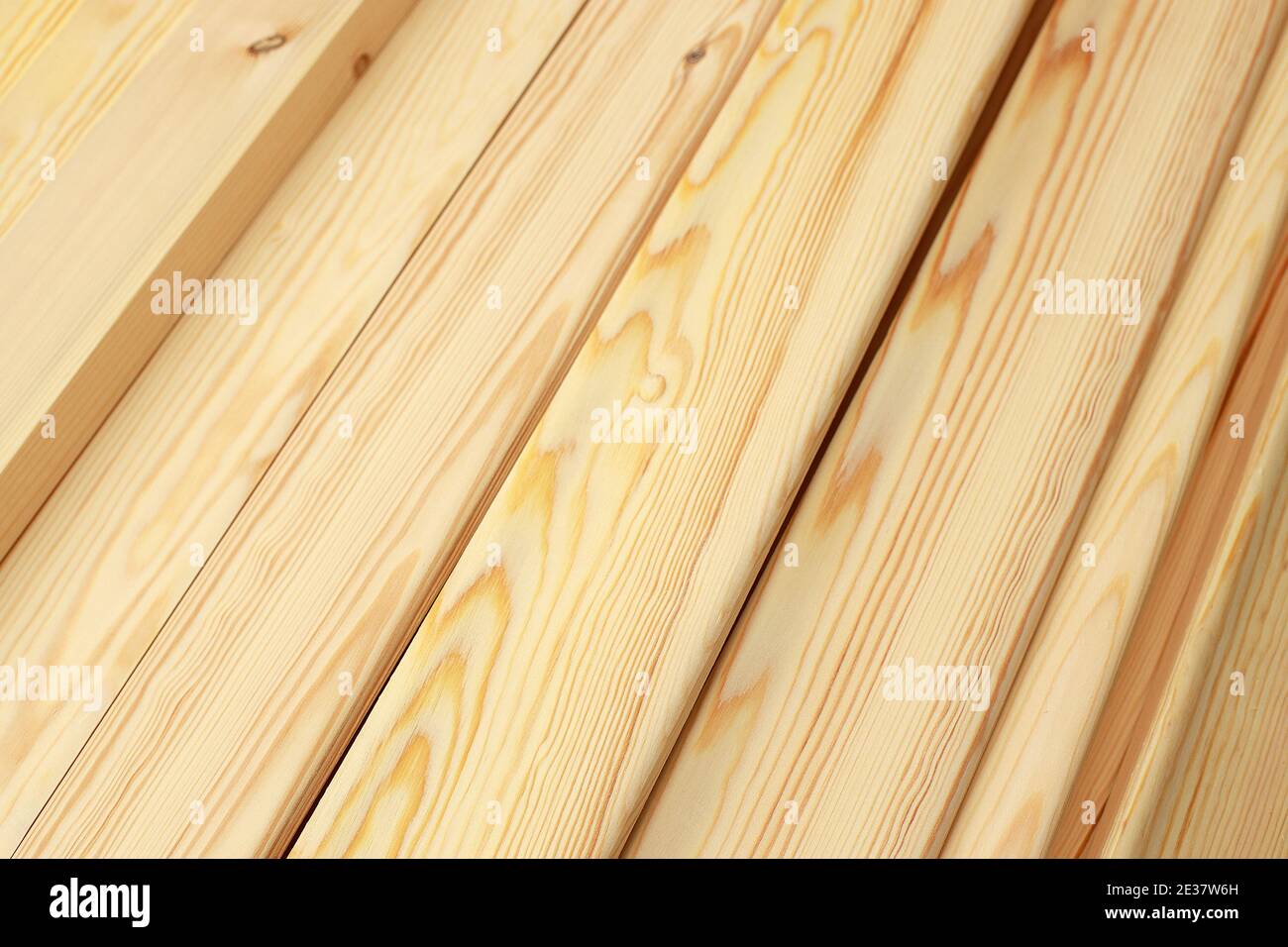 Narrow wooden slats or boards in close-up lie in a stack. This is a noble polished wood in the carpentry shop.  Stock Photo