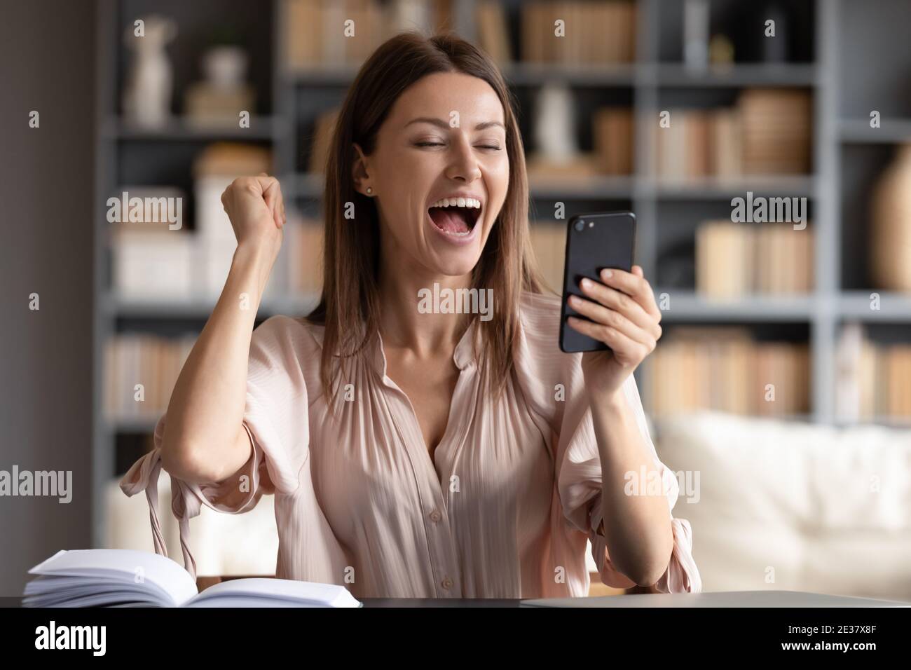Close up overjoyed woman looking at phone screen, celebrating success Stock Photo