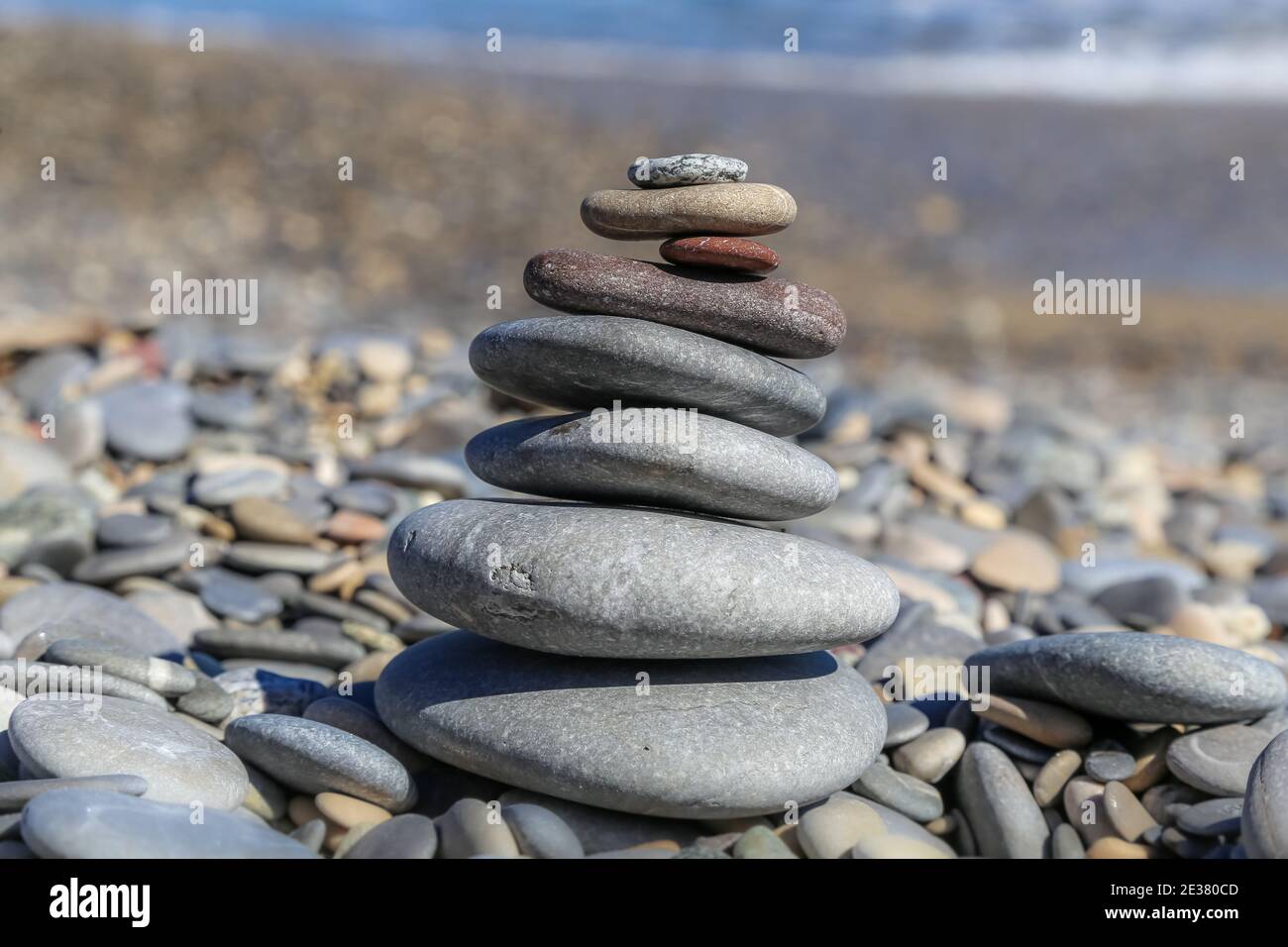 Selective focus of colourful stones stacked like a pyramid which has become a regular sight at local beaches centre of focus on a beach Stock Photo