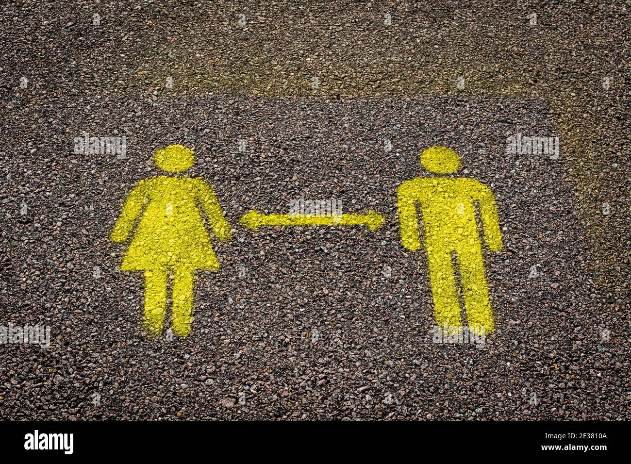 Yellow male and female figure painted on the ground to remind of social distancing Stock Photo