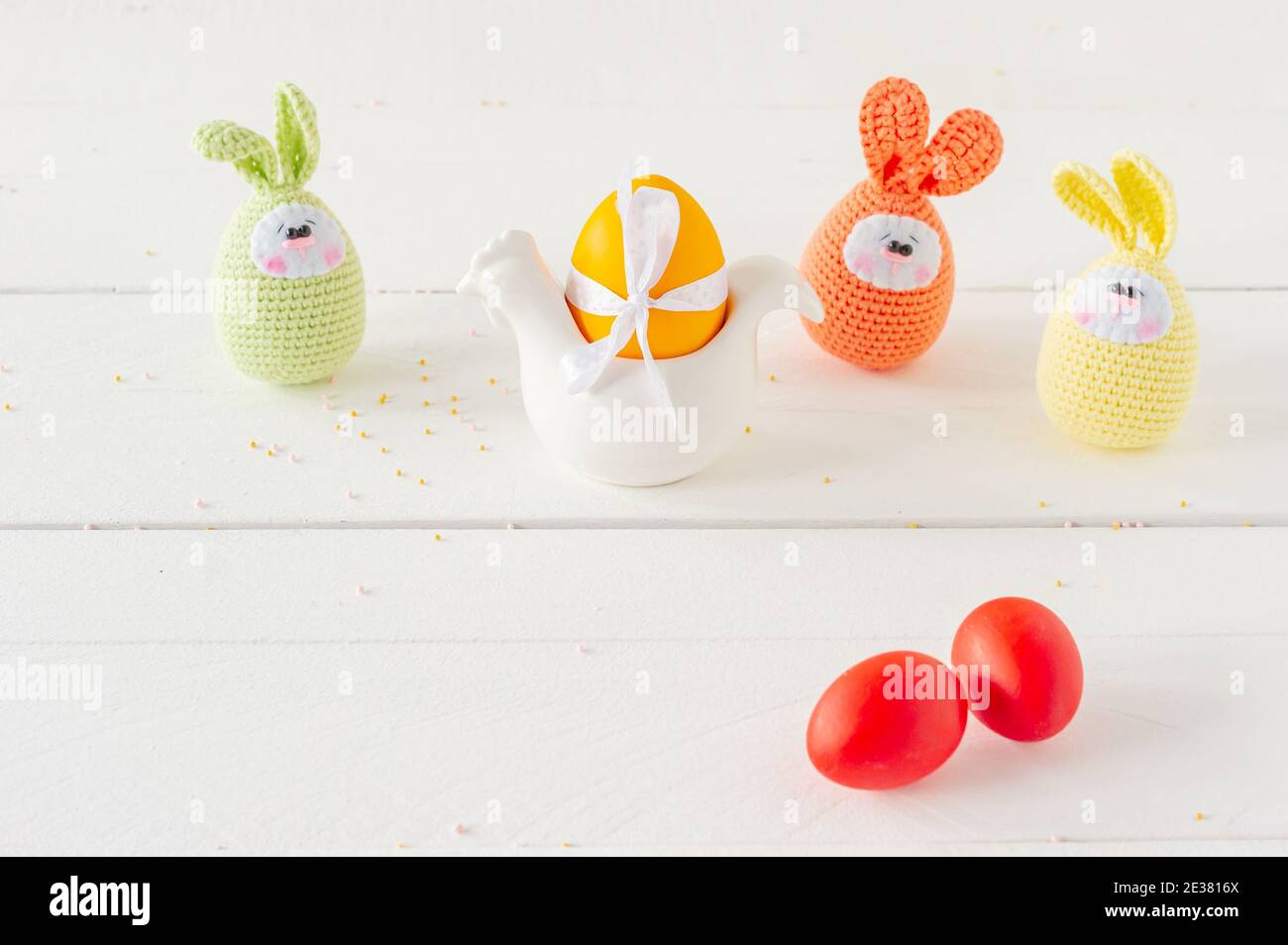 Arrangement decoration Happy Easter holiday background concept. Easter painted eggs with handmade knitted eggs on white wooden table. Pastel colors Stock Photo