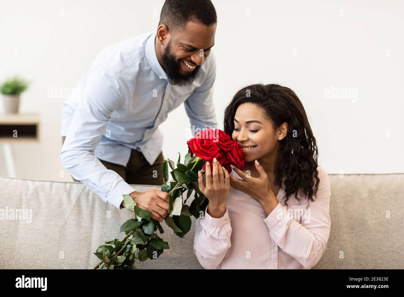 Young black man giving bunch of red roses to woman Stock Photo Alamy
