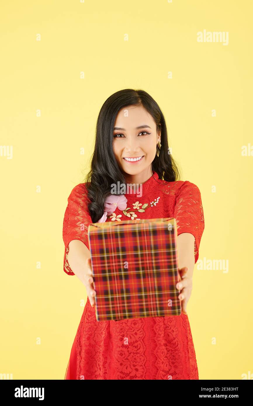 Cheerful pretty young Asian woman outstretching hands with big present for Chinese New Year celebration Stock Photo