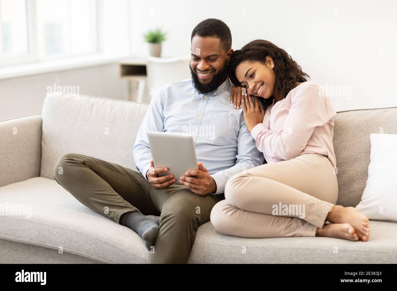 African american couple sitting on couch, using tablet Stock Photo - Alamy
