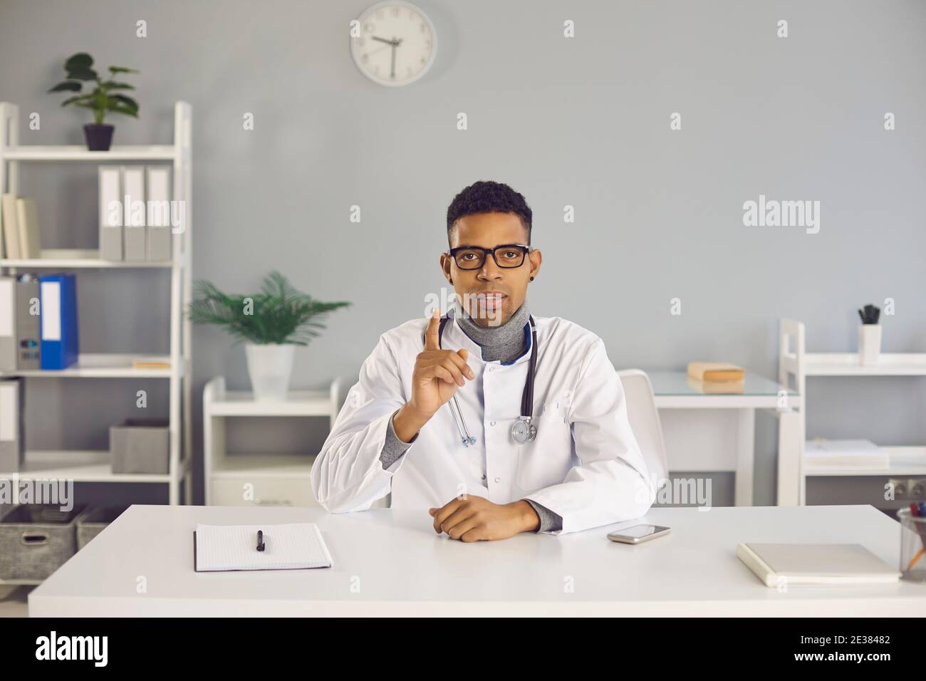 Doctor sitting at desk, telling about treatment and giving health recommendations Stock Photo