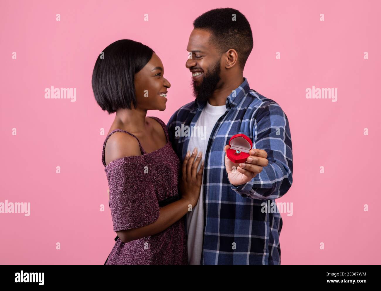 Affectionate black couple hugging and holding box with engagement ring on  pink background, selective focus Stock Photo - Alamy
