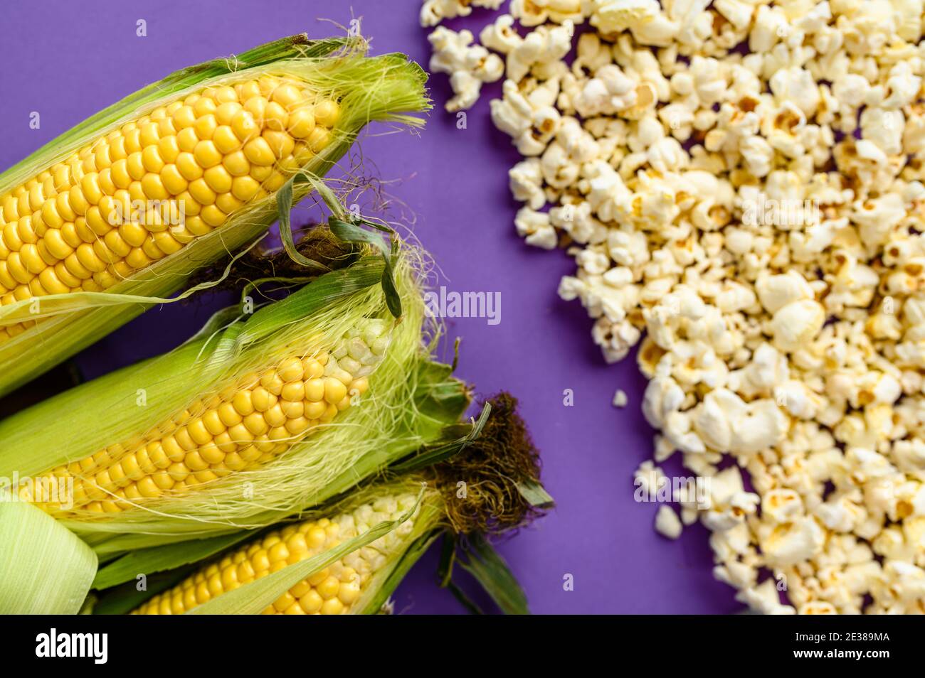 Corncobs and popcorn isolated on purple background Stock Photo