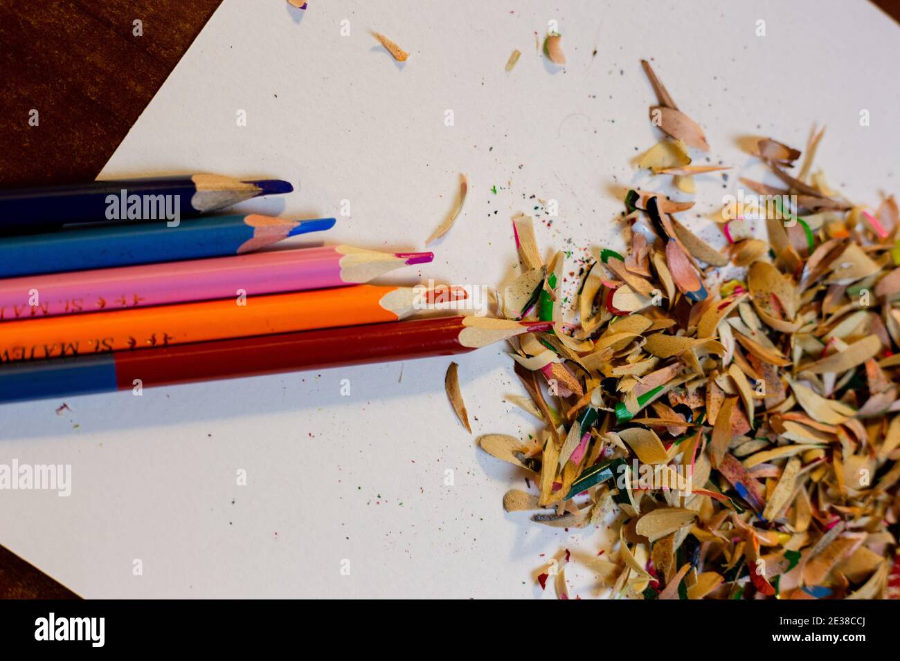 Colored pencils and shavings after sharpening pencils on a white sheet