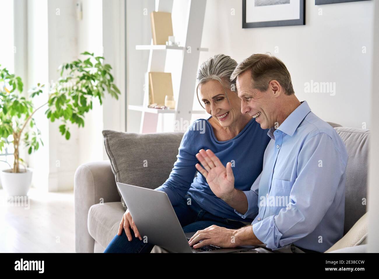 Happy old grandparents couple waving hand making online video call on laptop. Stock Photo
