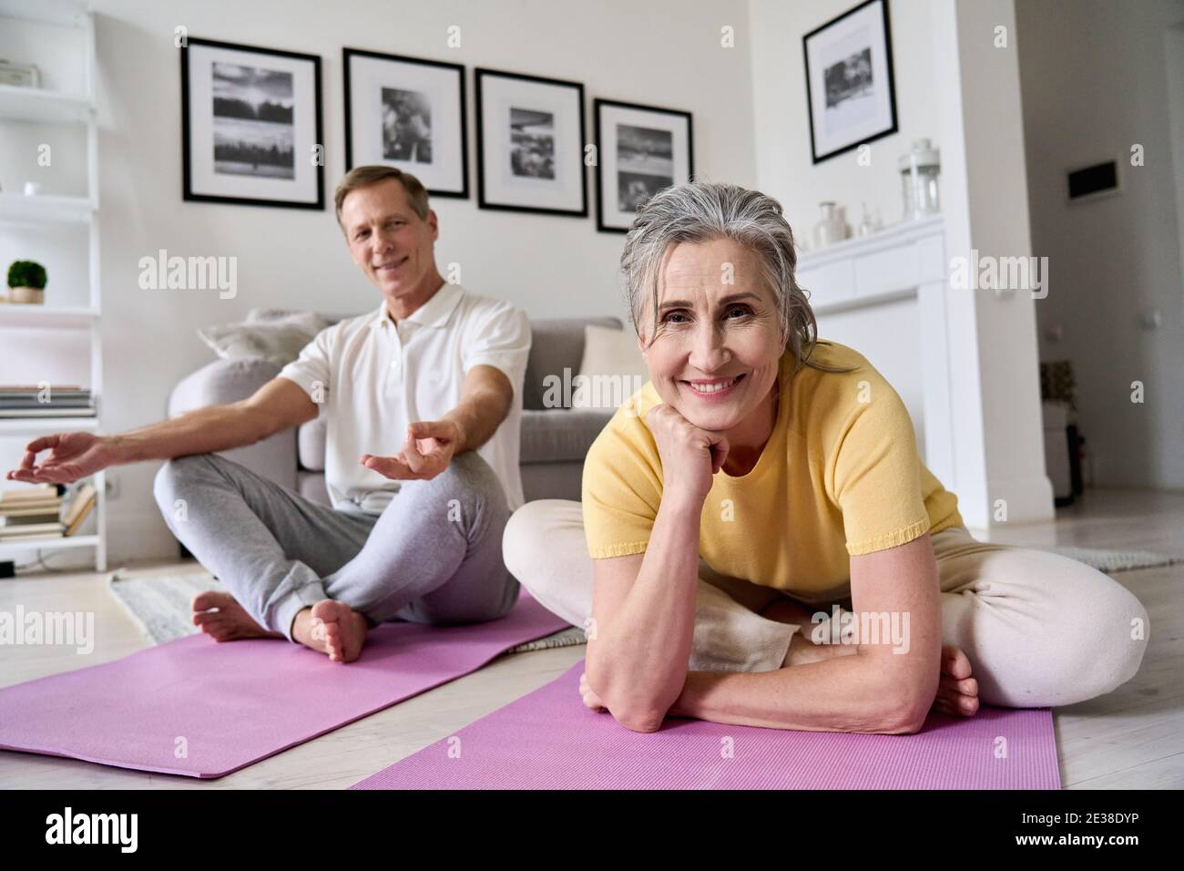 Happy fit middle aged woman exercising with husband at home, portrait. Stock Photo