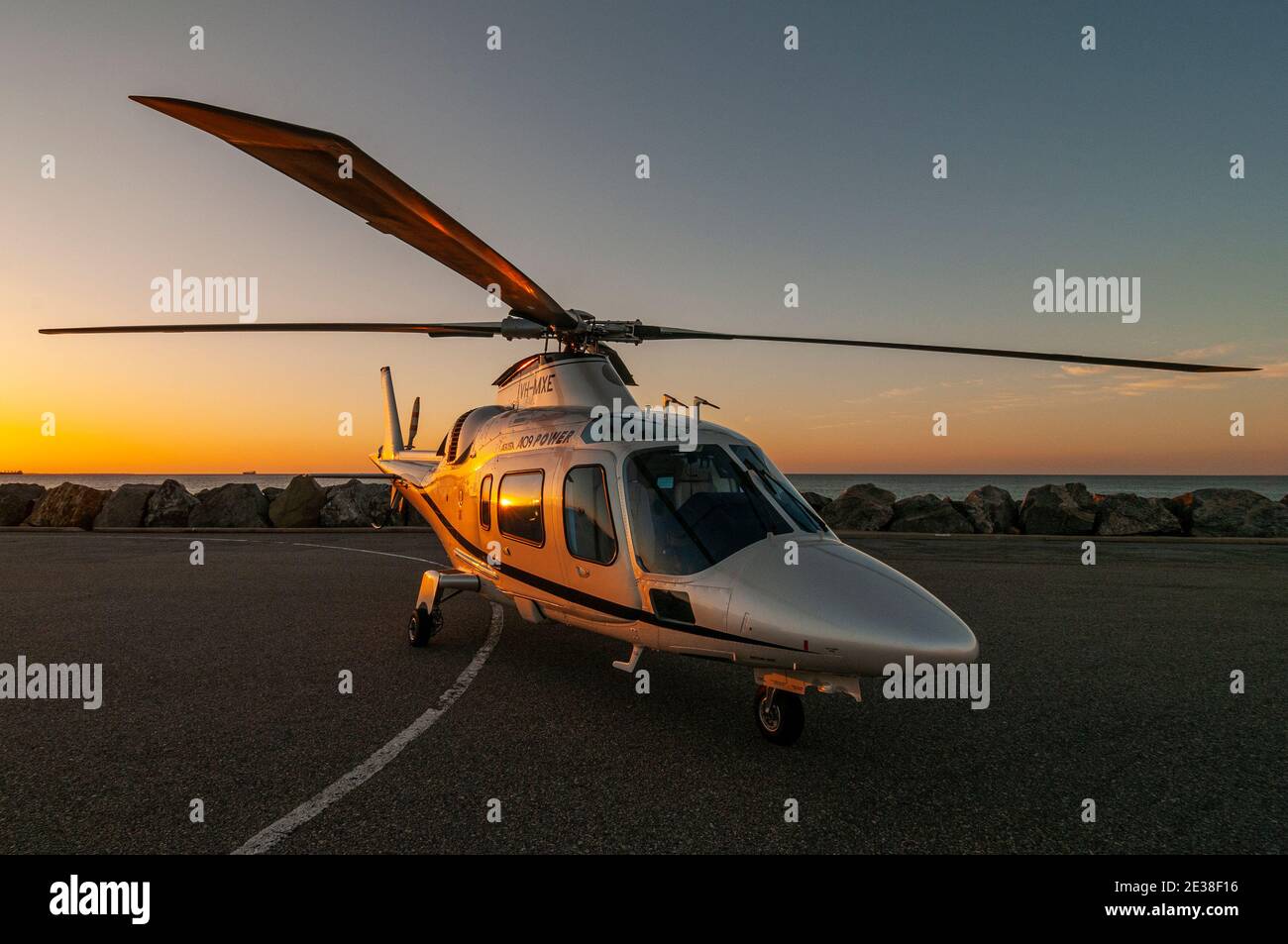 An Agusta 109 Power executive helicopter at sunset. Stock Photo