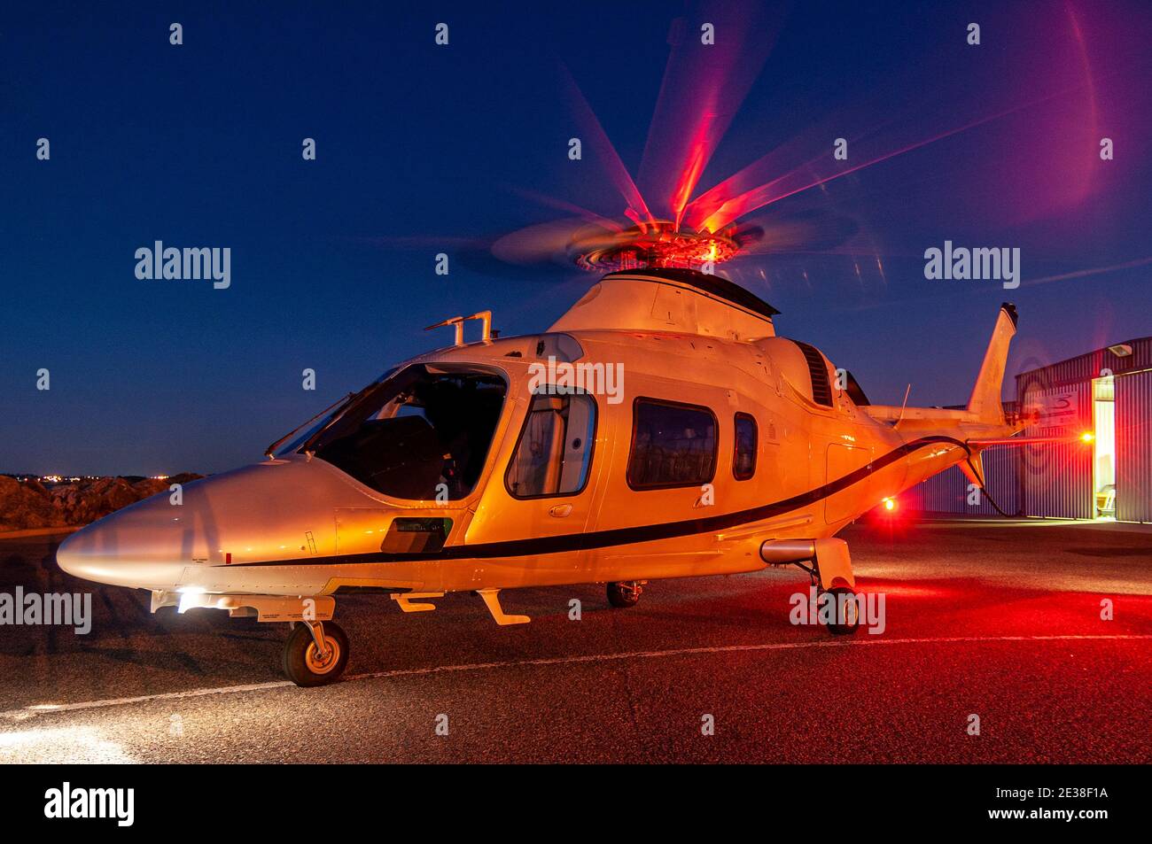 An Agusta 109 Power executive helicopter at sunset. Stock Photo