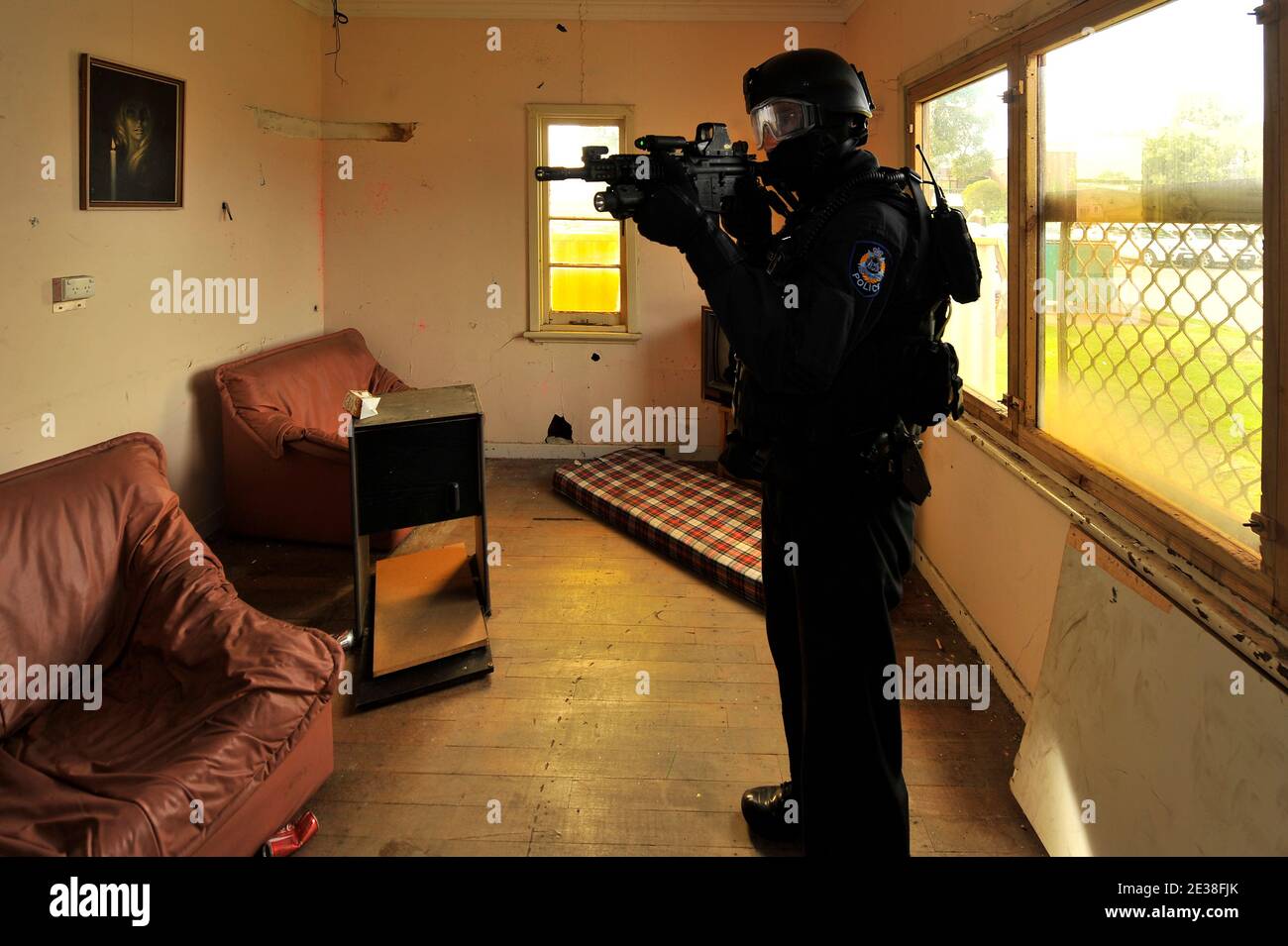 Police Tactical Response officers with laser sighted automatic weapons in action inside a house. Stock Photo