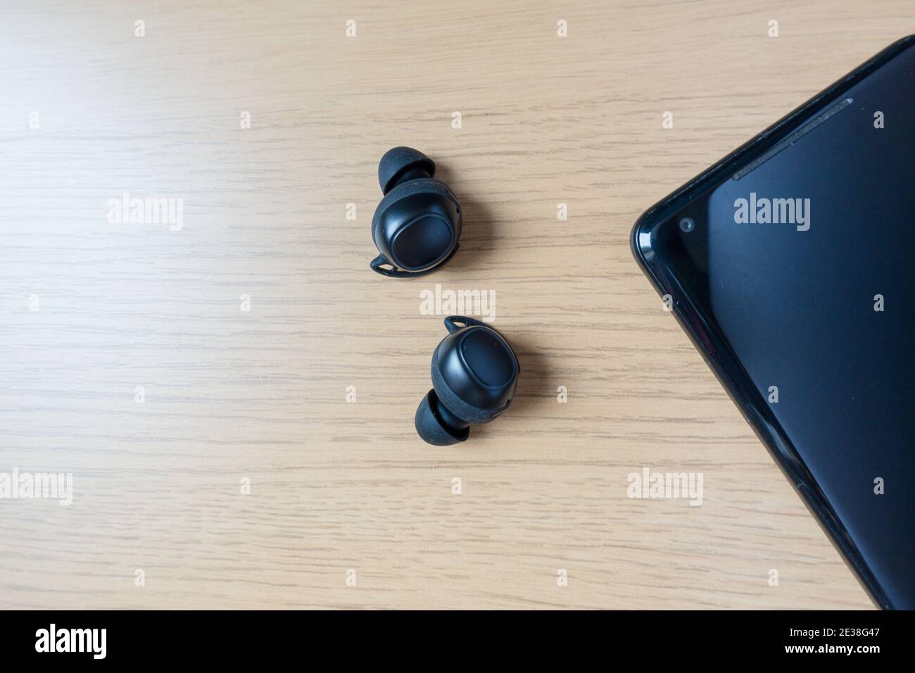 Earbuds or Ear Buds next to a phone on table Stock Photo
