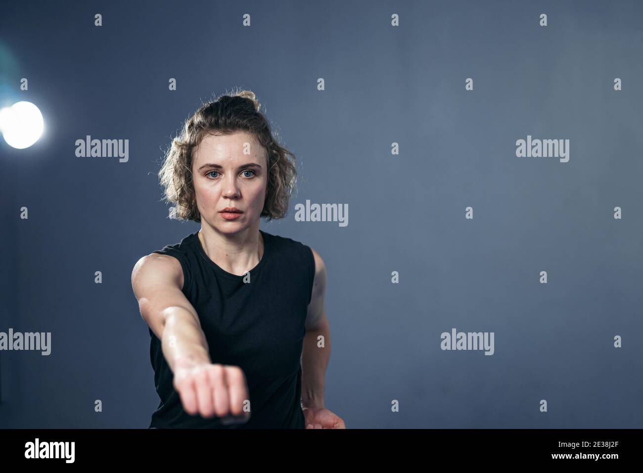 Caucasian young woman practicing mixed martial arts, throw punches