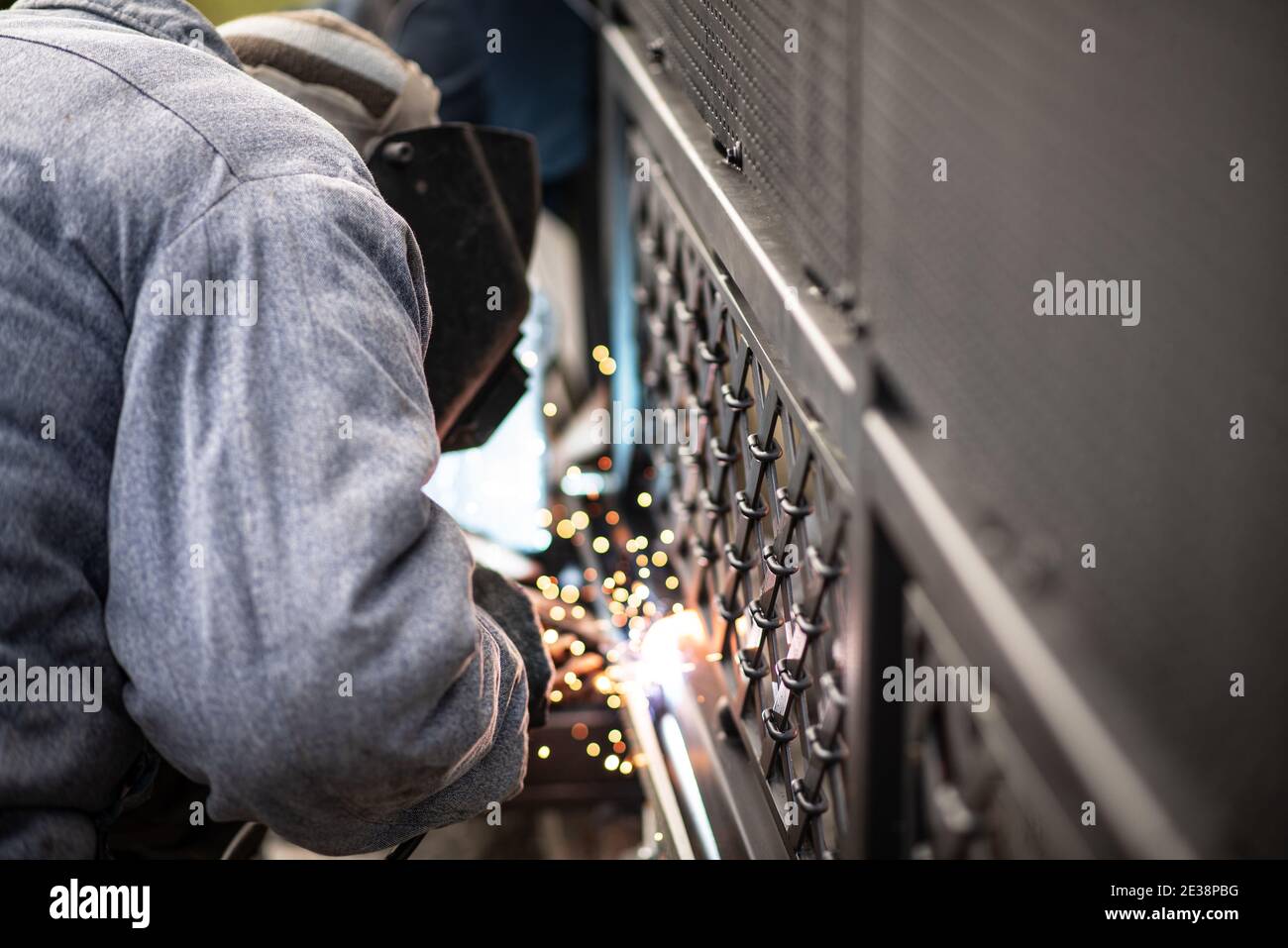 Professional worker performs work on start of sliding gate. Process of welding metal rack