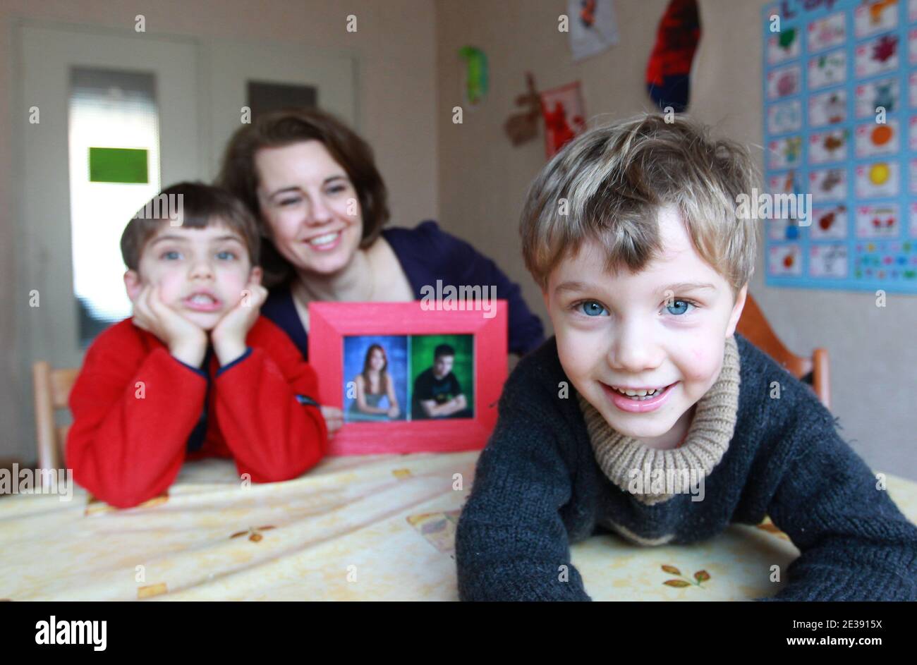 EXCLUSIVE. Nathalie Gettliffe poses with her two sons Jean-Philippe (L) and  Martin Gruzelle while holding a photograph of Josephine and Maximilien, her  children living in Canada, at her home in Strasbourg, eastern