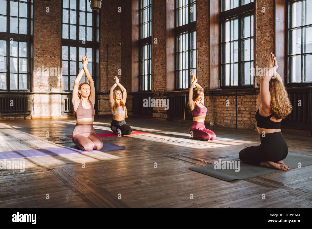 Asanas In Group Group of young women wearing sporst wear do complex of stretching yoga ...