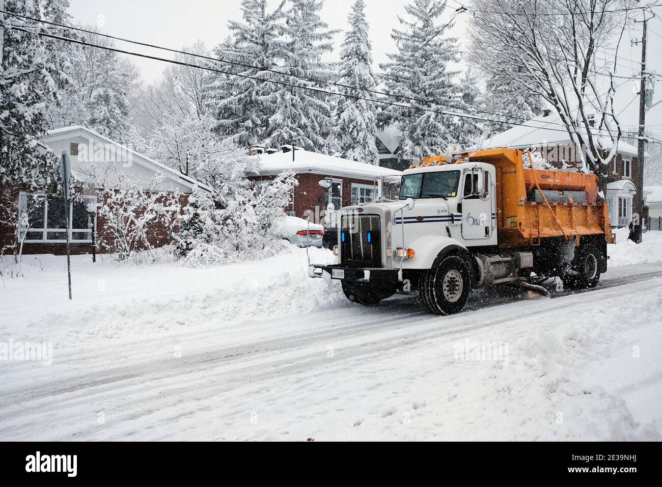 A yellow City of Ottawa snow plow truck roams the Glebe streets during a fresh dumping of 25cm. Ottawa, Ontario, Canada. Stock Photo