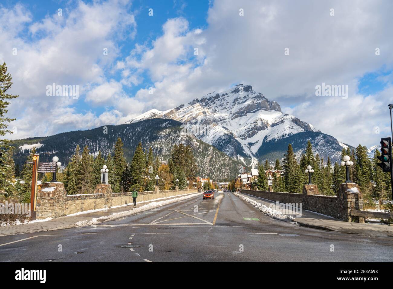 Banff Avenue in snowy autumn sunny day. Snow-covered Cascade Mountain with blue sky and white clouds in the background. Banff National Park Stock Photo