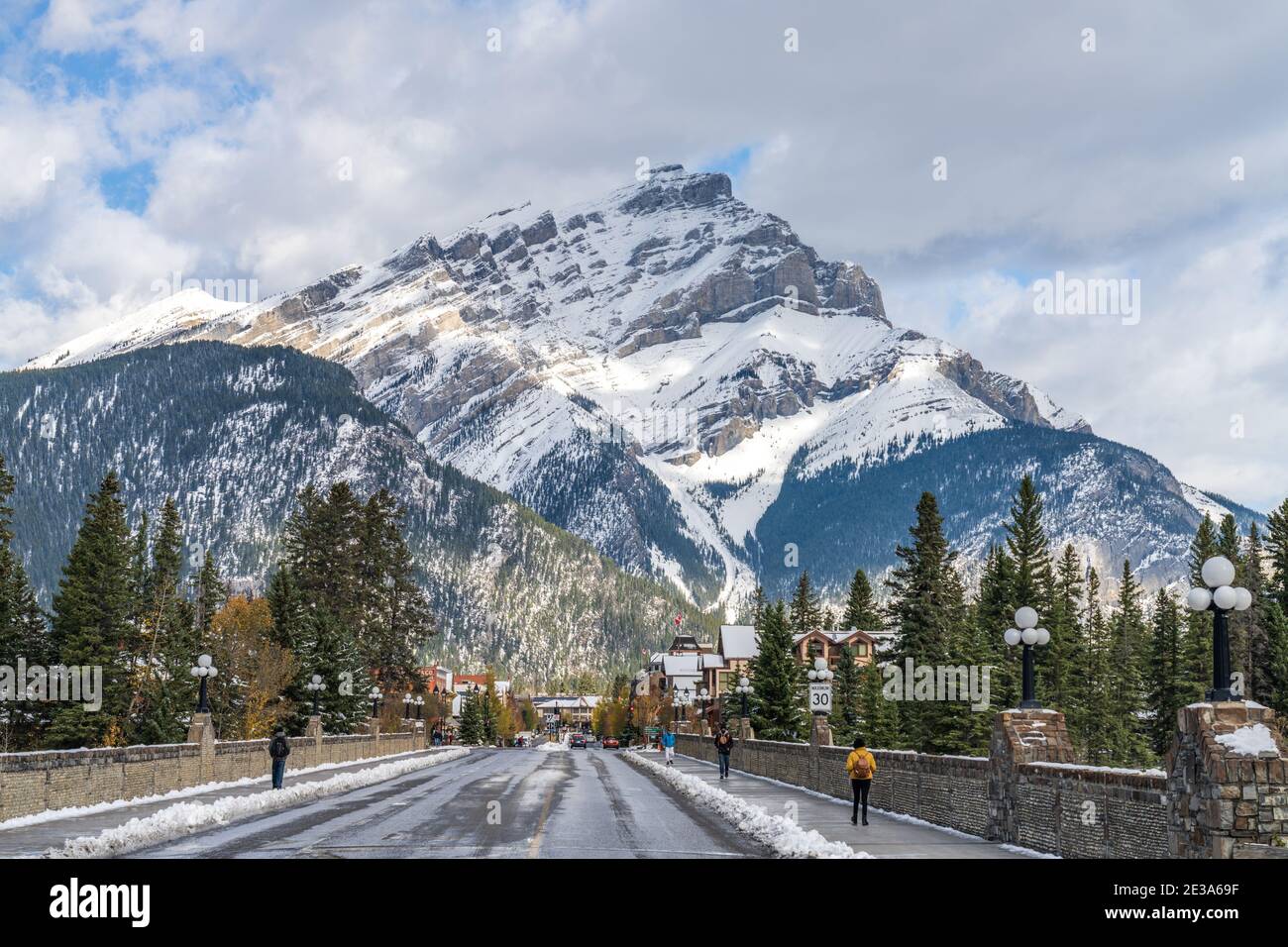 Banff Avenue in snowy autumn sunny day. Snow-covered Cascade Mountain with blue sky and white clouds in the background. Banff National Park Stock Photo
