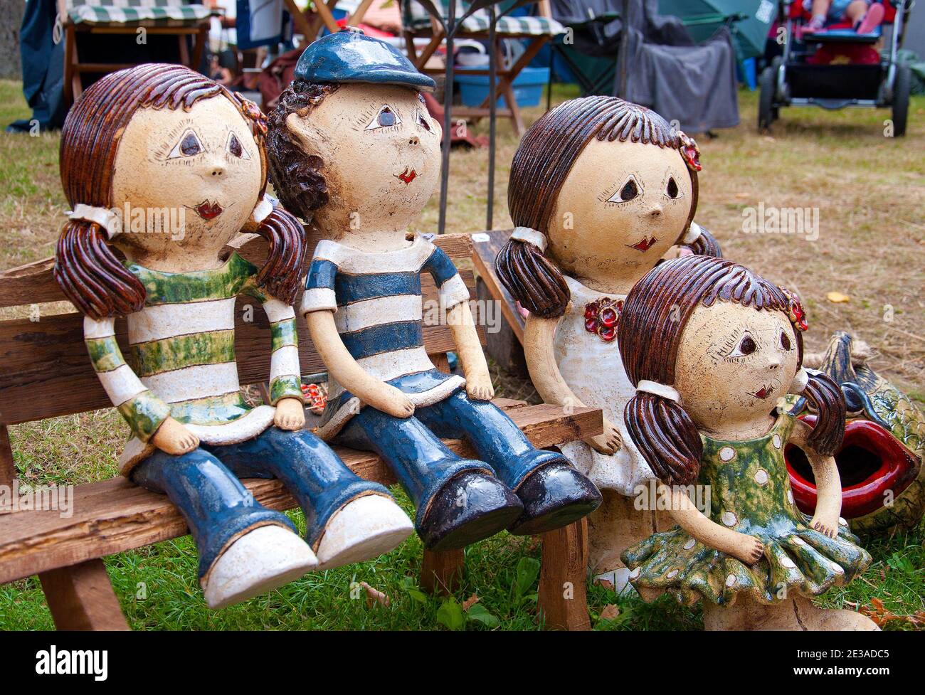 Family with children sitting on a bench. Ceramic marionettes. Traditional craft. Stock Photo