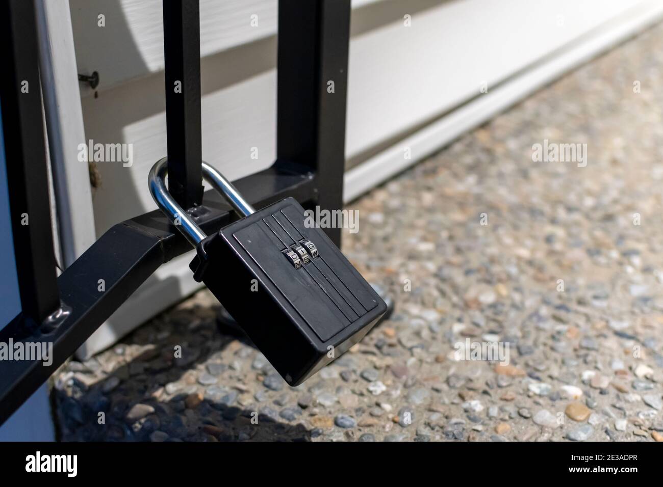 A closed combination lock or padlock attached to an iron gate at a home. Stock Photo
