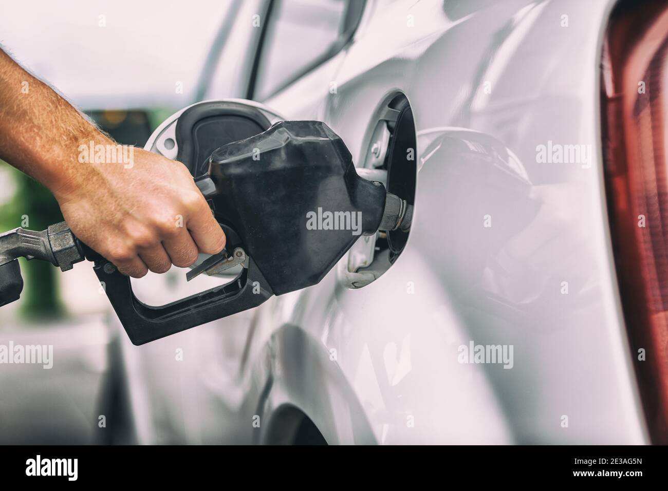 Car pumping gas at gas pump. Closeup of man pumping gasoline fuel in