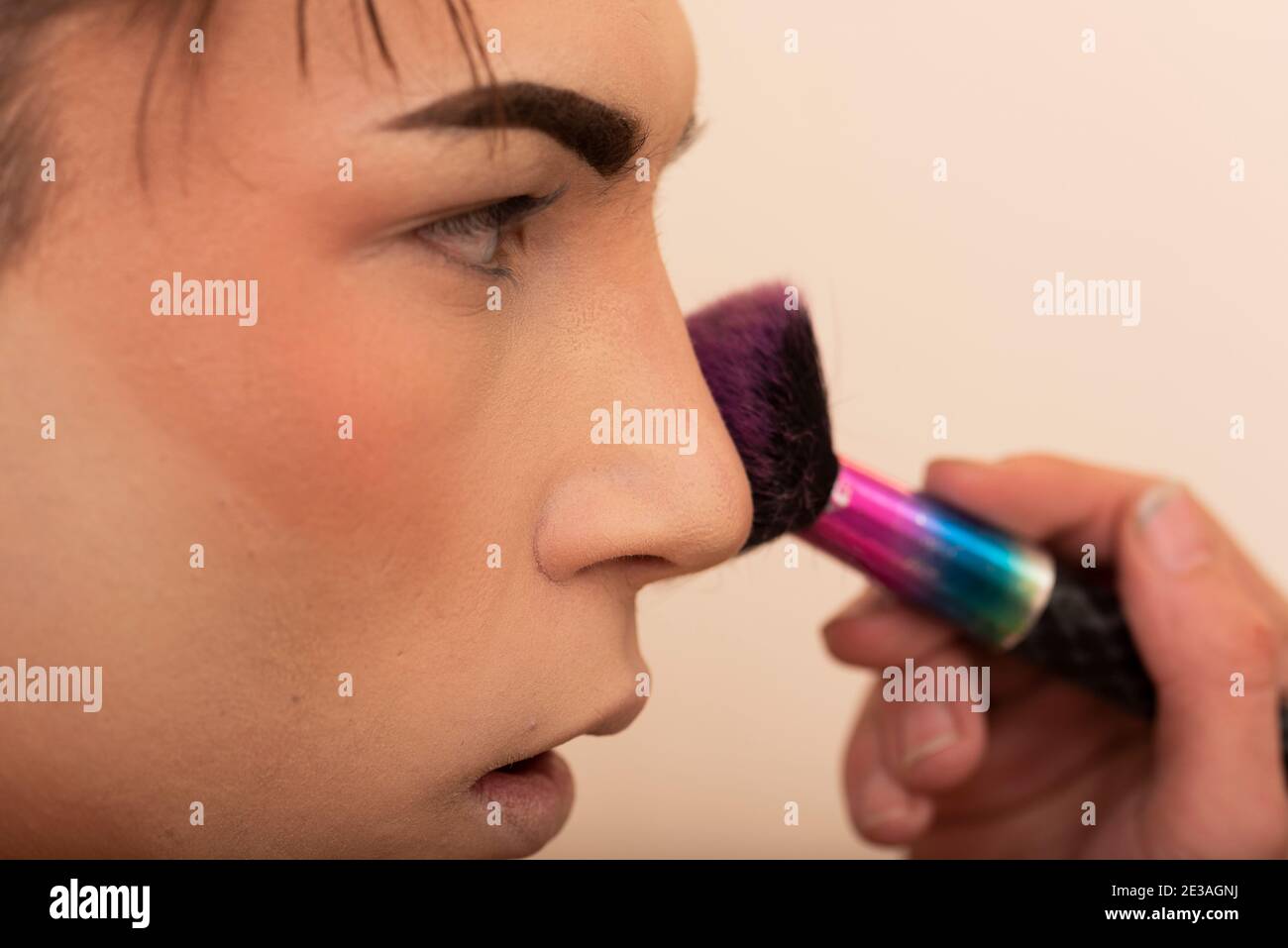 close-up of a young man applying makeup with brush Stock Photo