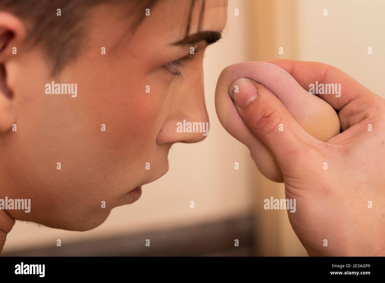 close-up of young man putting on makeup with sponge Stock Photo