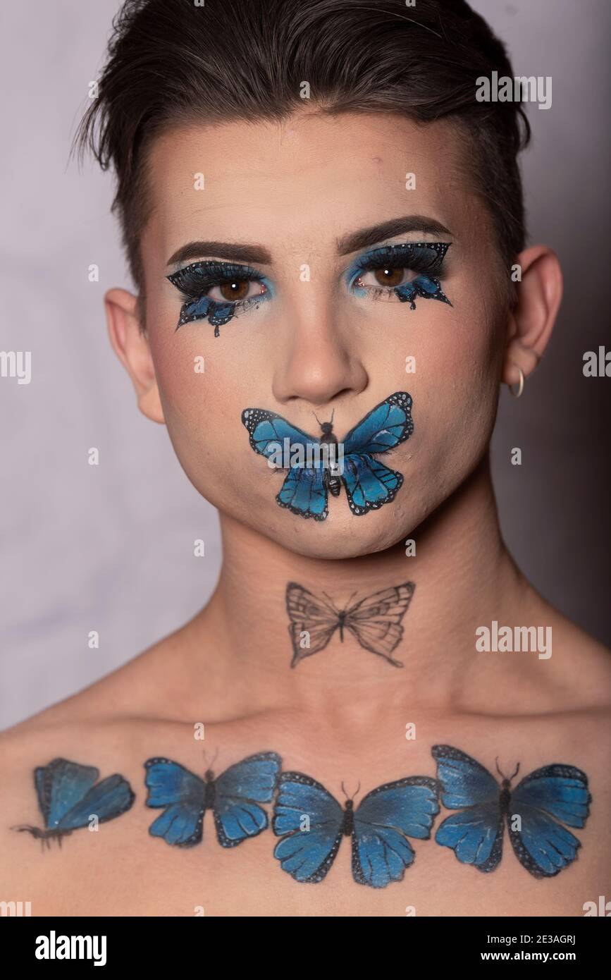 young model man with artistic makeup of blue butterflies on a white background Stock Photo