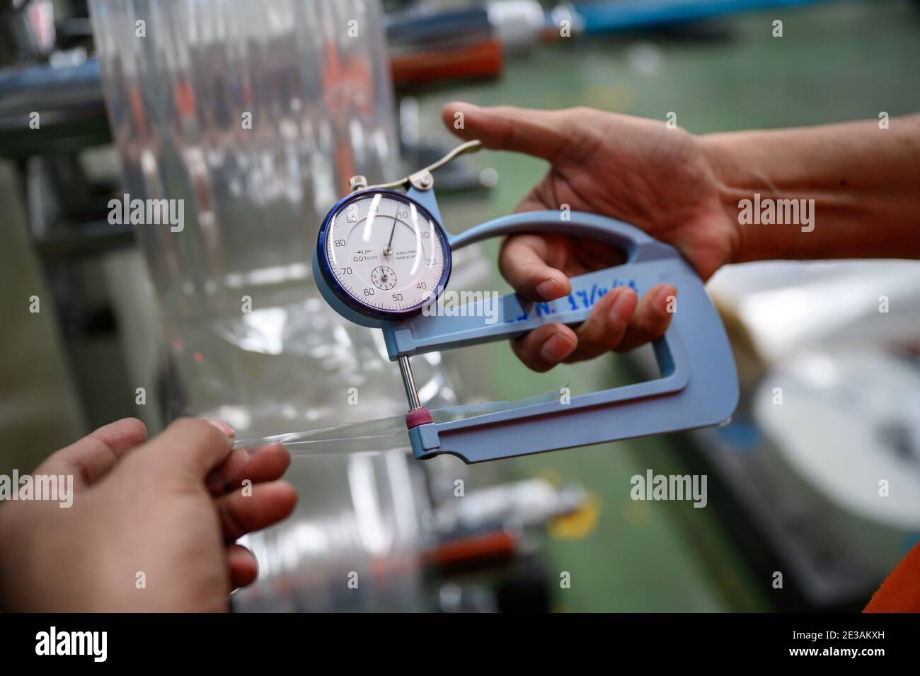 Man's hand is measuring the thickness of the plastic bag type film Polypropylene To check and control the quality Before being used to produce plastic Stock Photo