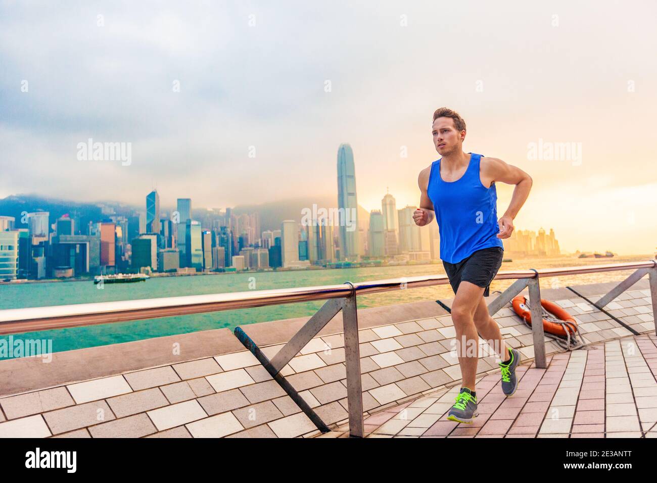 Running man runner in Hong Kong city urban skyline. Caucasian athlete training cardio jogging on the promenade of Victoria Harbor in HongKong, China Stock Photo