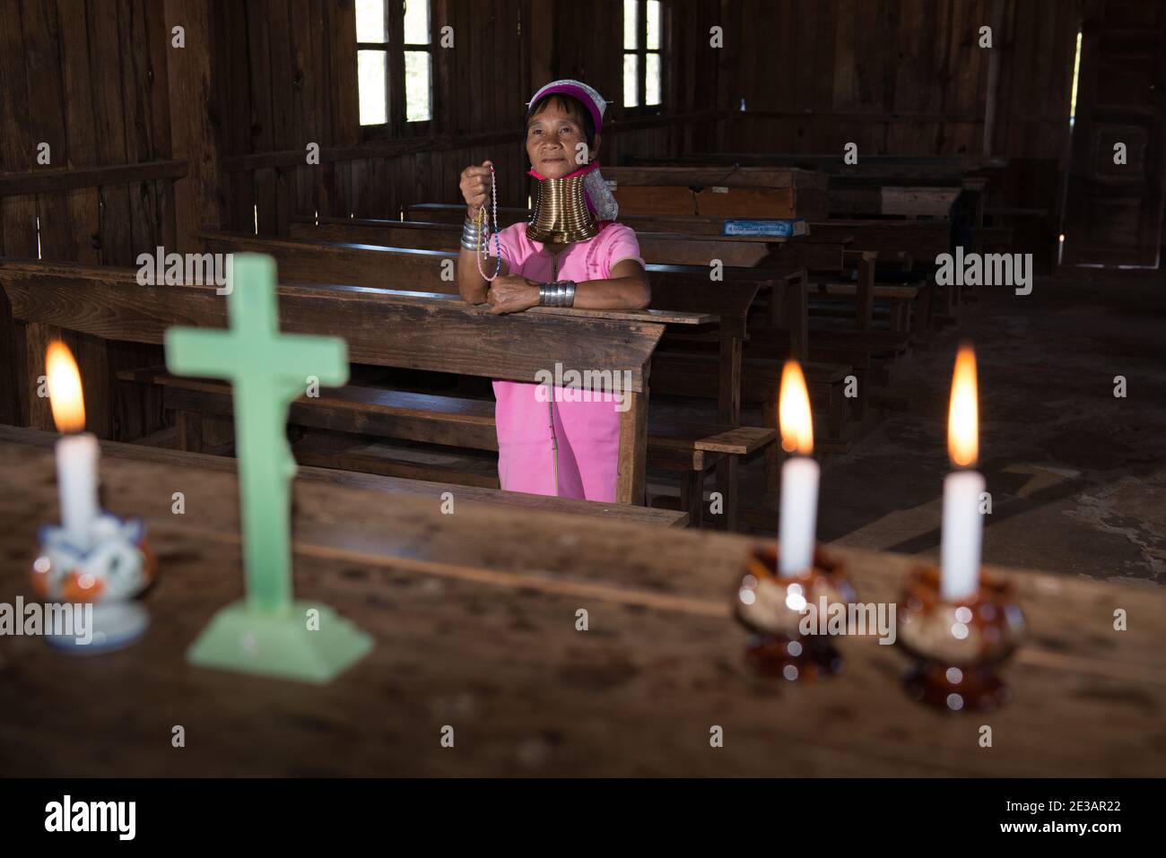 Myanmar, Loikaw, Panpet: Woman of Kayan Lahwi tribe praying the rosary in an old wooden church. Stock Photo