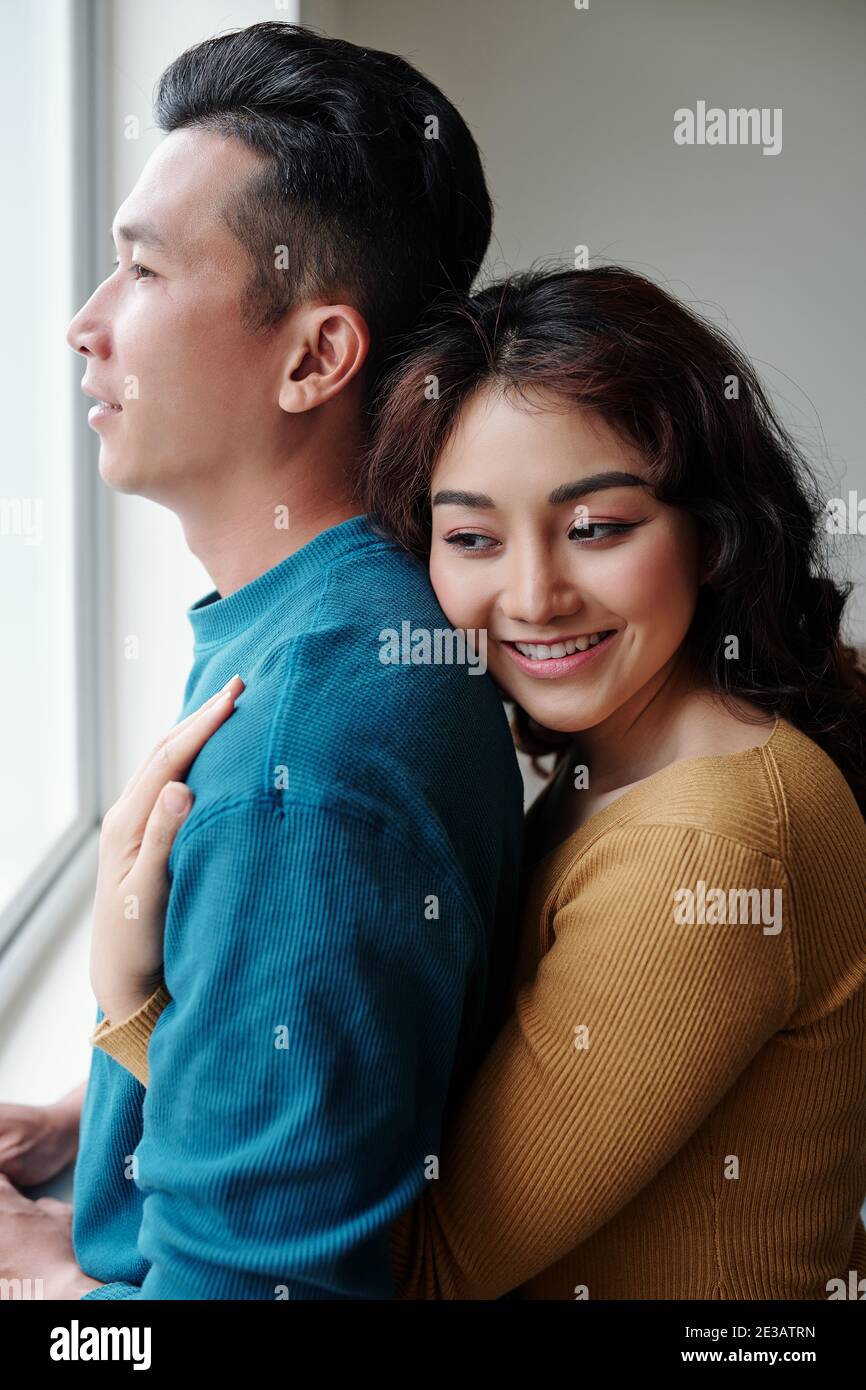 Happy pretty young woman hugging her husband from behind when they are ...