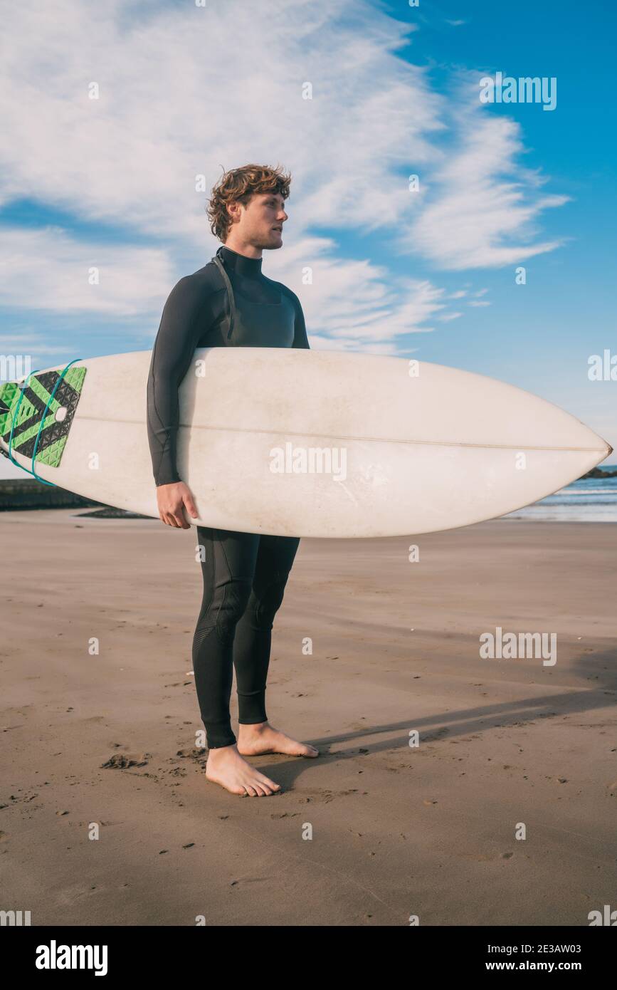 Surfer standing in the ocean with his surfboard Stock Photo - Alamy