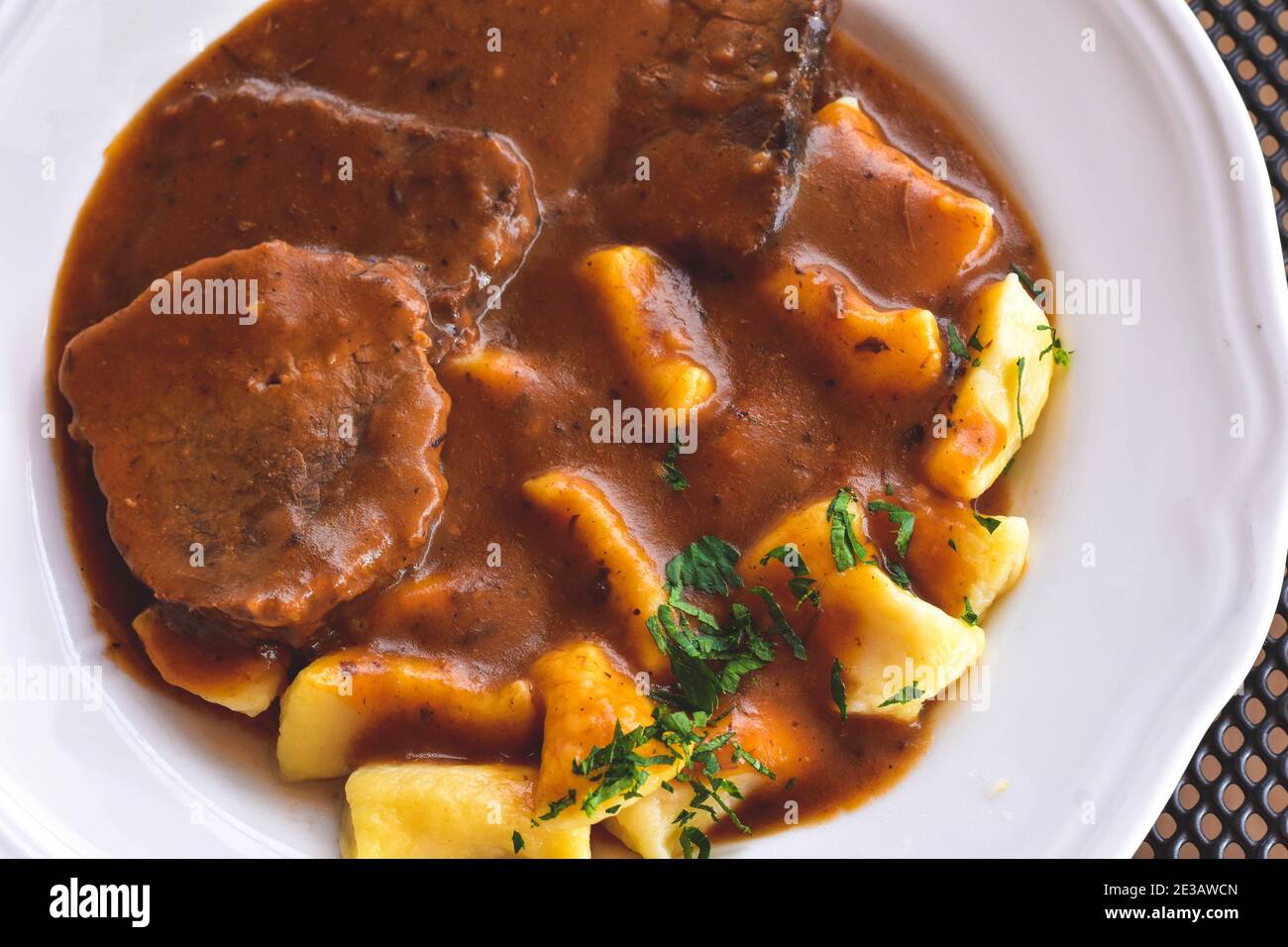 Pasticada With Gnocchi - Dalmatian Pot Roast or beef/ Croatian dish - Pasticada with gnocchi, beef stew in a sauce  at dark wooden background Stock Photo
