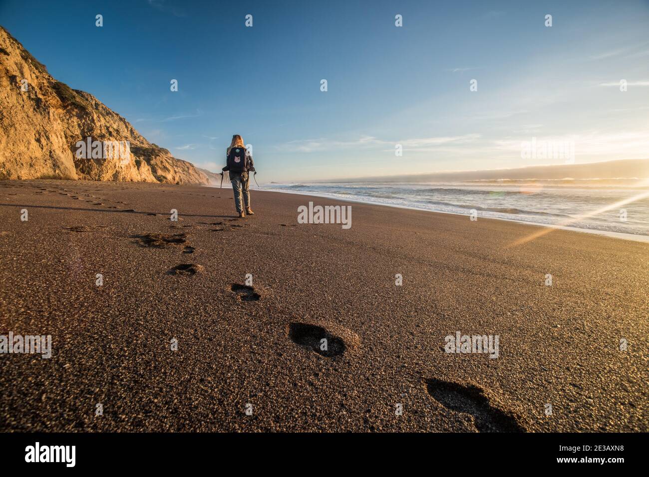 A female hiker walks down a California beach in the evening, a portion of the Alamere falls trail in Point Reyes National seashore. Stock Photo