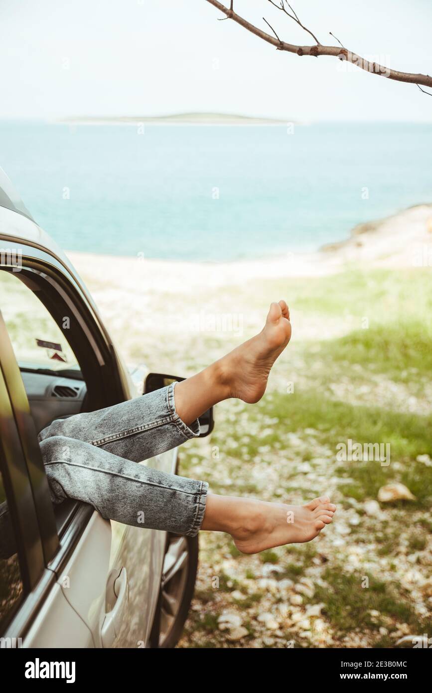 woman legs stick out from car window sea beach on background. summer ...