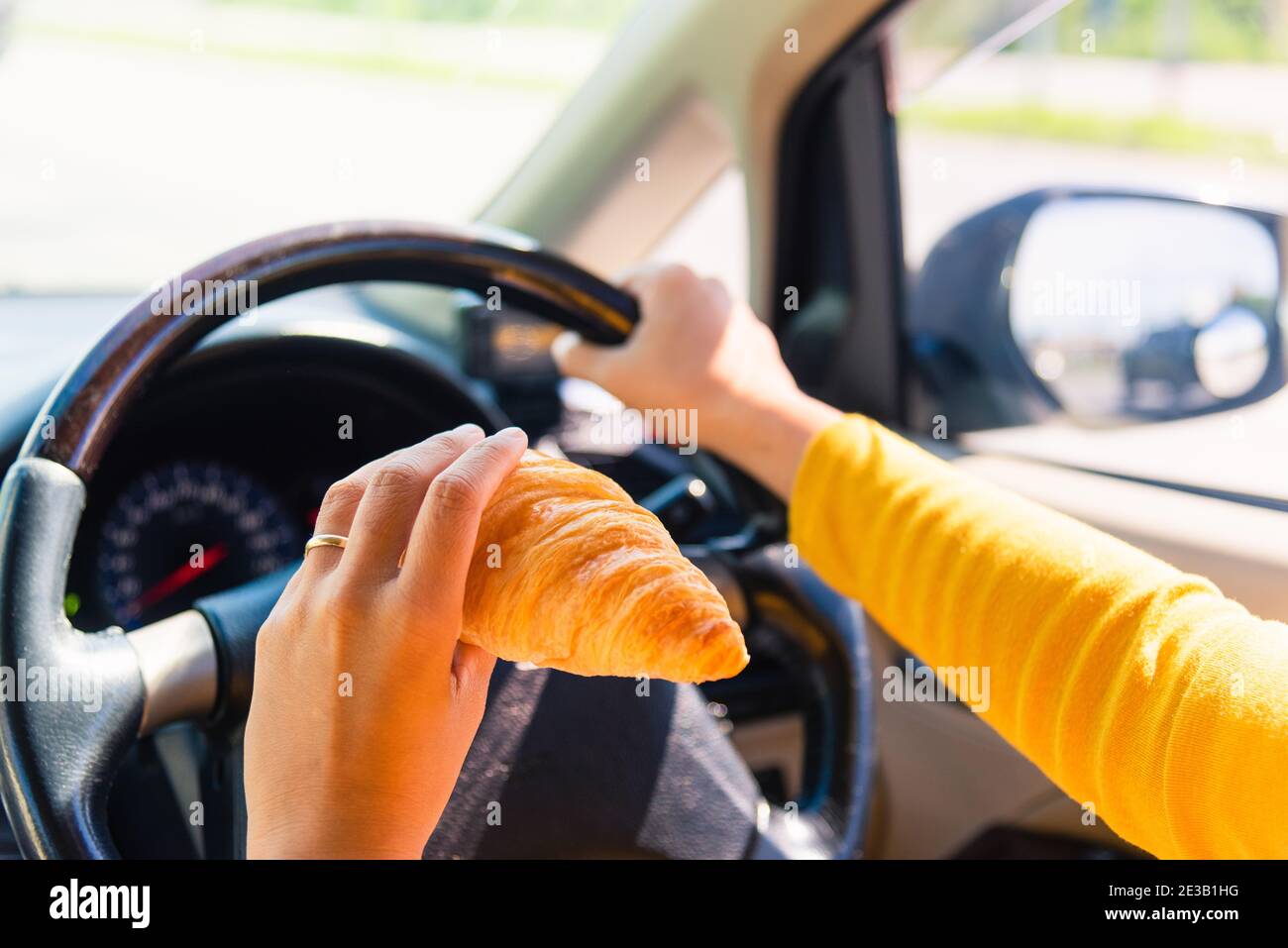 Asian woman eating food fastfood while driving the car in the morning