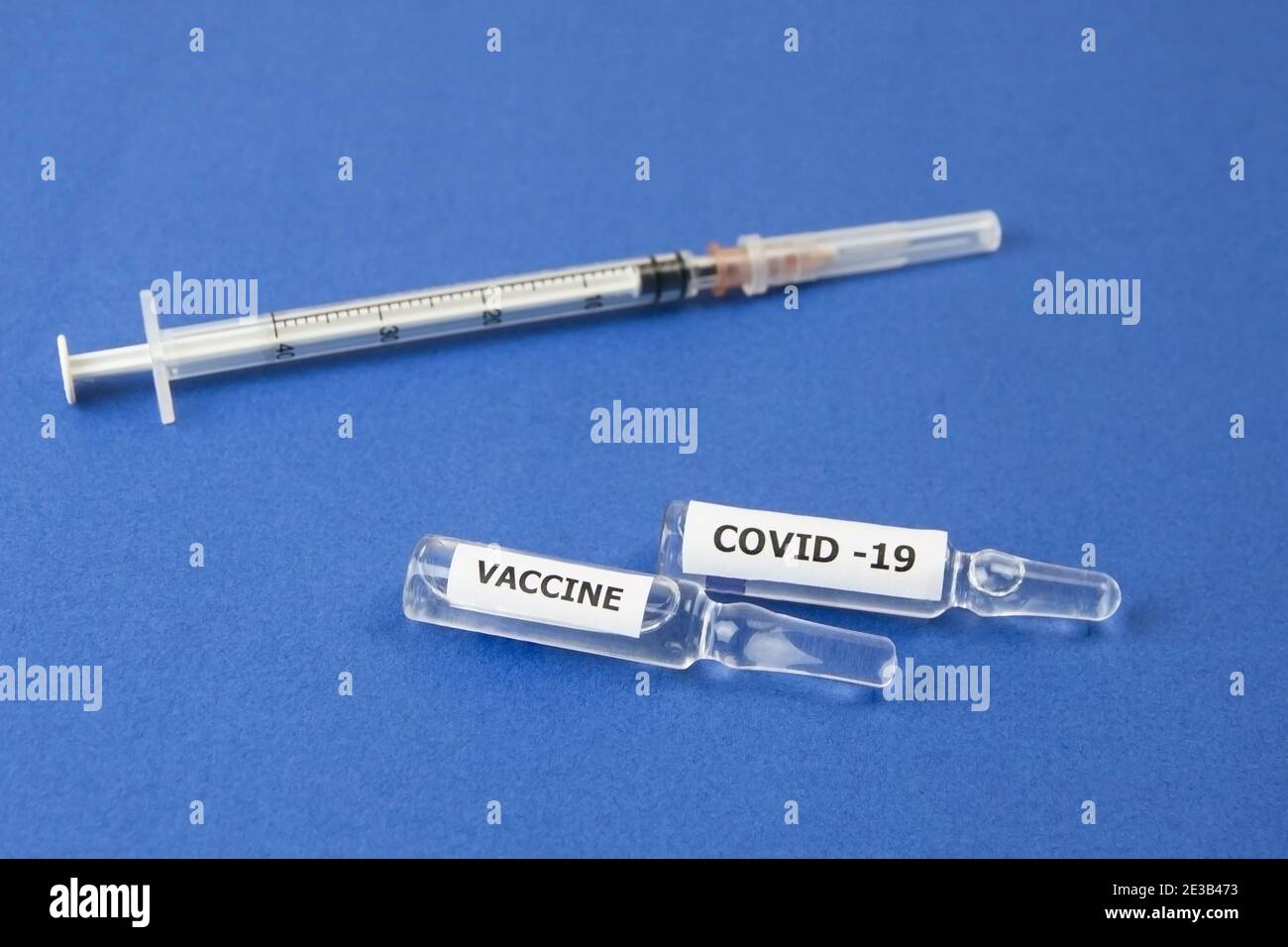 On a blue background lies a syringe and ampoules with the Covid-19 ...