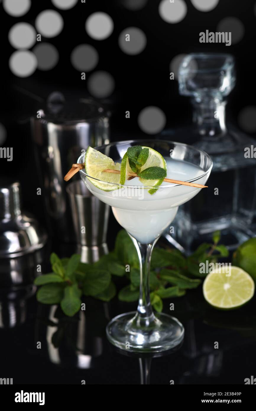 Tequila, Citrus liquor, lime juice - this is a Margarita cocktail. A  of lime with a sprig of mint decorates a glass. Dark  moody food Stock Photo