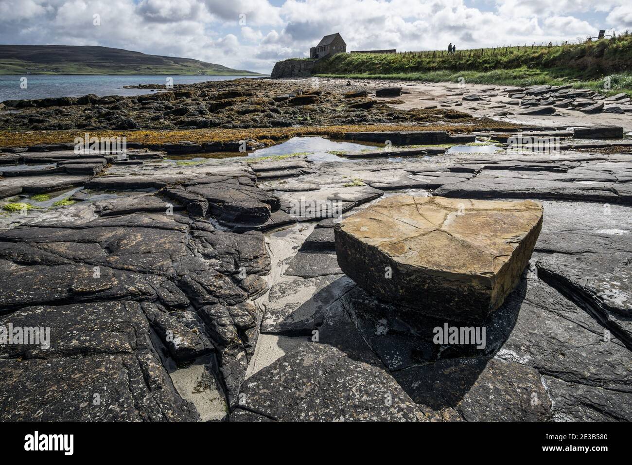 View of the rocks and beach at the Broch of Gurness, the Iron Age village  on Orkney. Rocks, sea and Rousay island visible in the distance Stock Photo