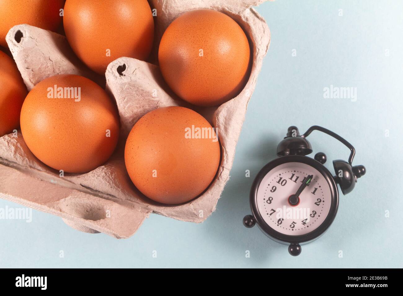 Hen eggs in an egg carton and black alarm clock Stock Photo Alamy