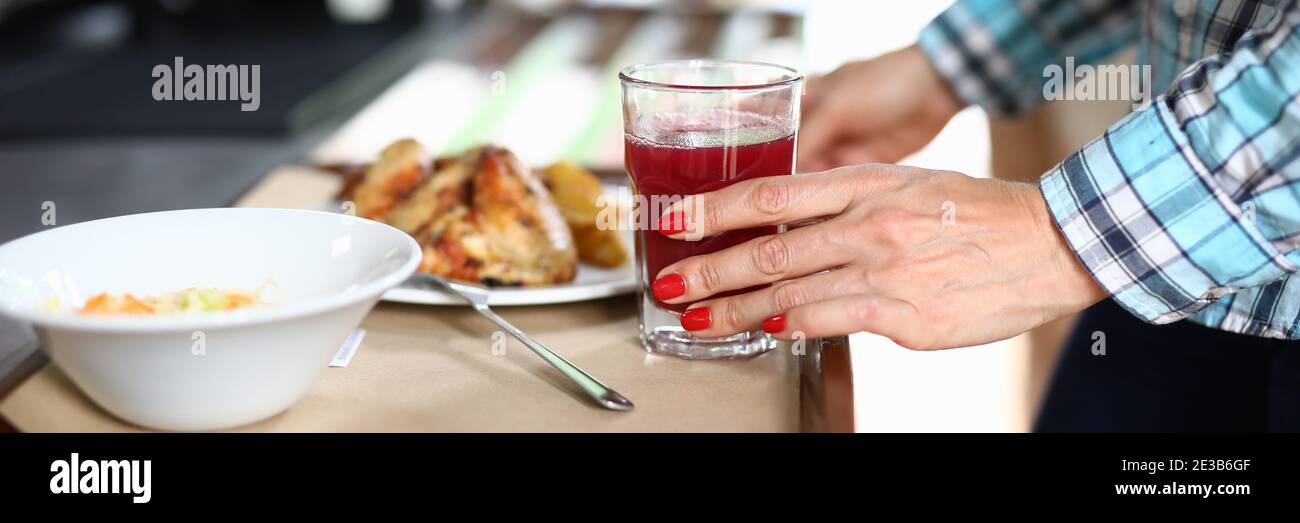 There is salad on tray and a second dish woman's hand holds glass with red liquid. Stock Photo