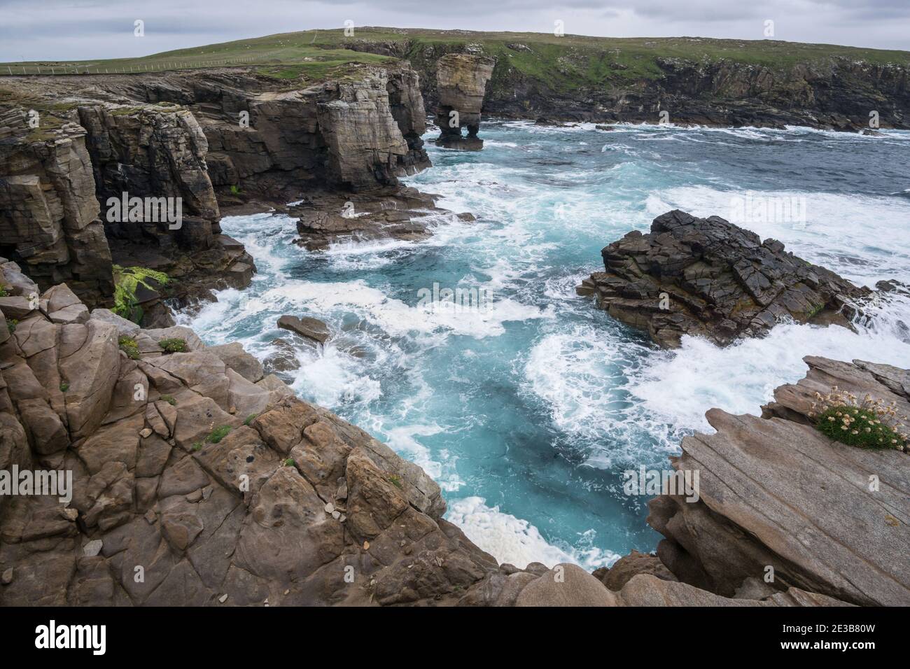 Waves crashing against the Yesnaby cliffs in Sandwick, Orkney, with the Yesnaby Castle sea stack visible in the centre Stock Photo