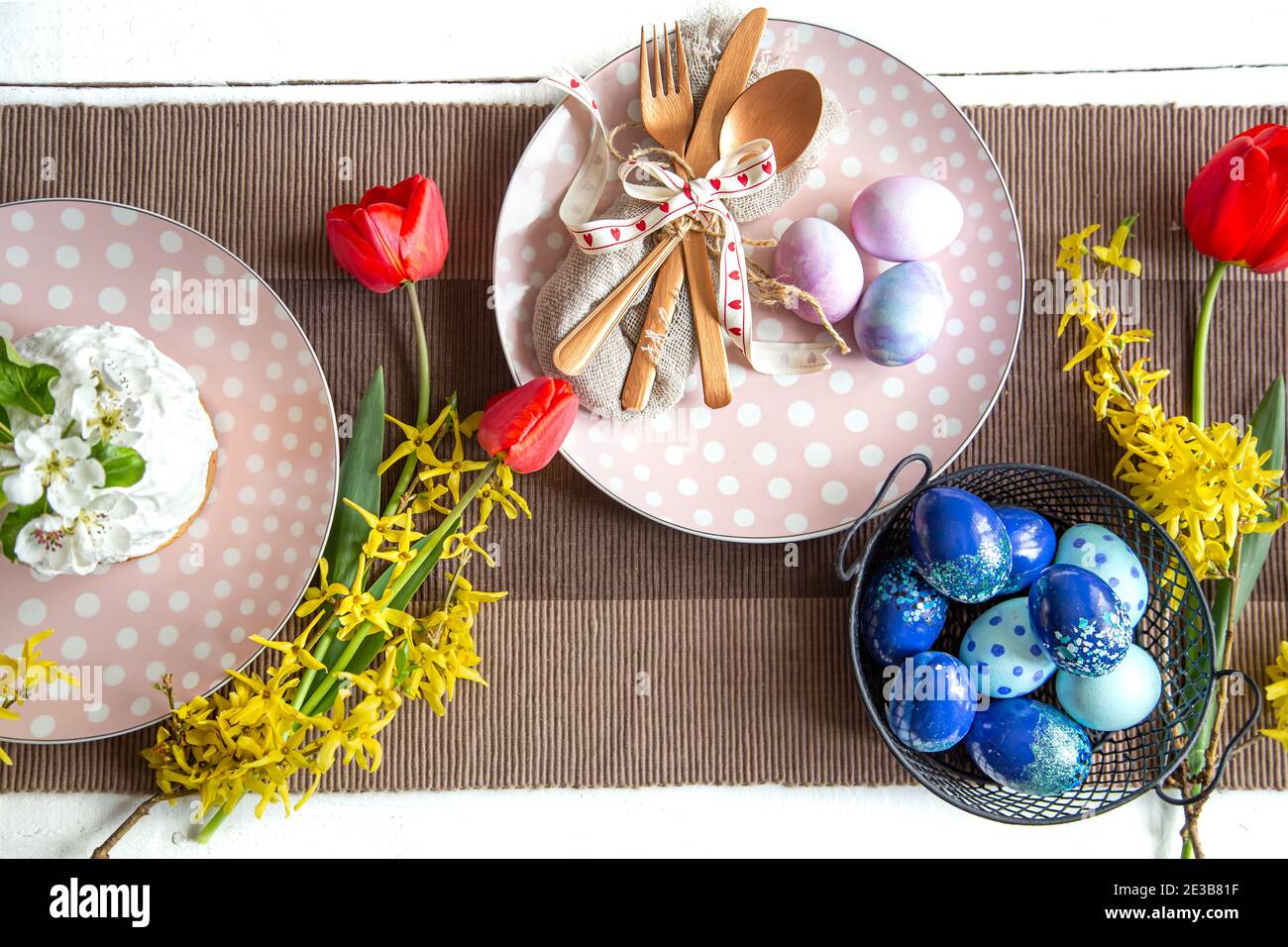 Plates with Easter cake, flowers and Easter eggs. Table setting for the Easter holiday. Stock Photo