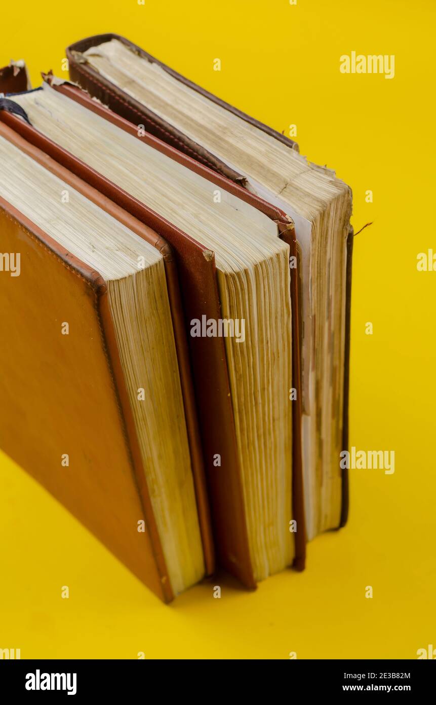 Three old dailies standing on endpaper on yellow background. The diaries have worn pages. Stock Photo
