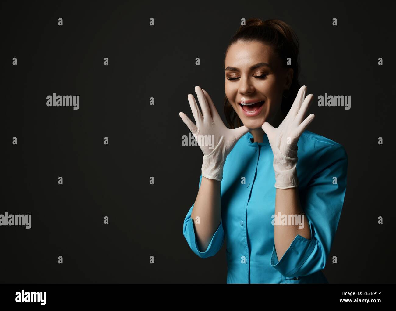 Young brunette woman doctor nurse in blue medical gown and latex gloves ...